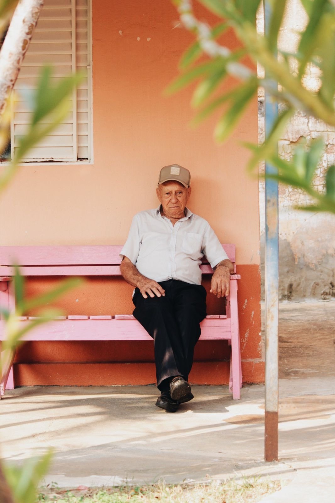 Retrato de um senhor sentado em um banco rosa